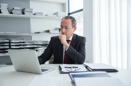 Businessman reviewing documents on laptop