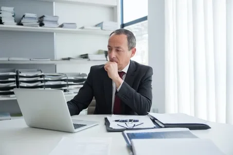 Businessman reviewing documents on laptop