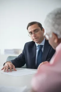 Financial advisor or lawyer reviewing contract with a senior client
