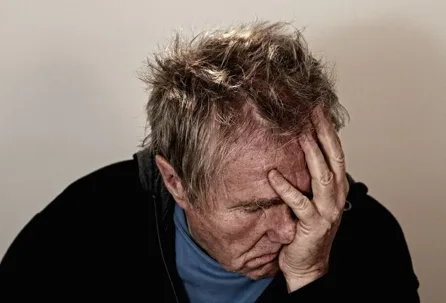 A man with messy hair rests his head in his hand
