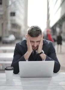 Stressed man holding face at laptop
