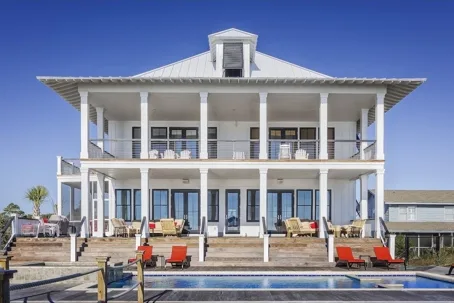 Large white coastal house with two-story porch and swimming pool