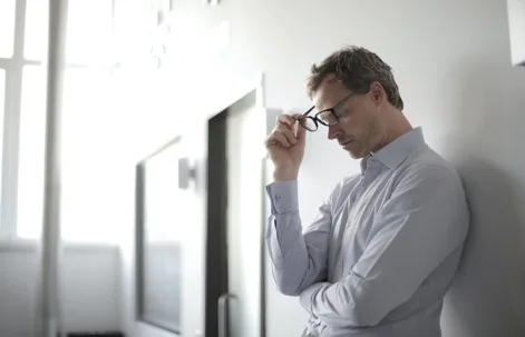 Stressed man holding glasses