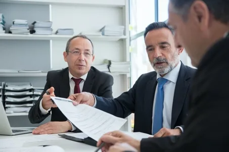 Business executives in suits reviewing and handing over a contract