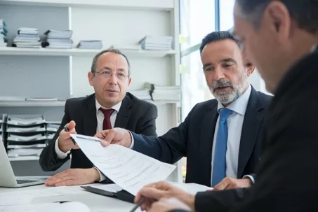 Business executives in suits reviewing and handing over a contract