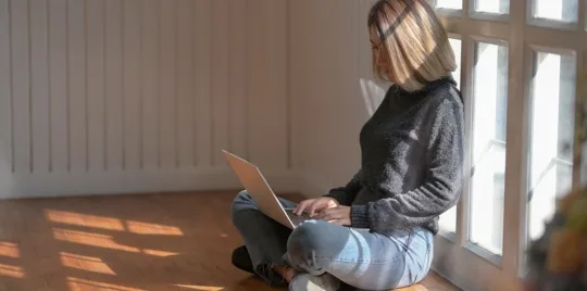 Woman sitting by window using a laptop