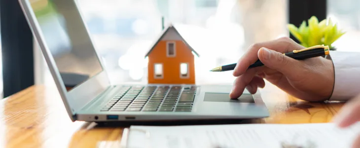 Hand using laptop with small house model
