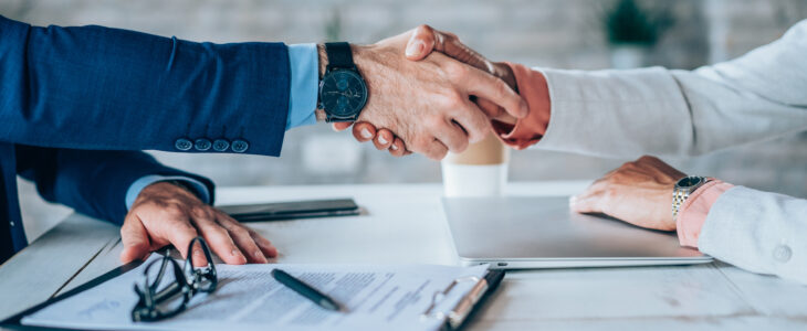 Cropped shot of unrecognizable business persons shaking hands after signing a contract. Business people shaking hands in the office.