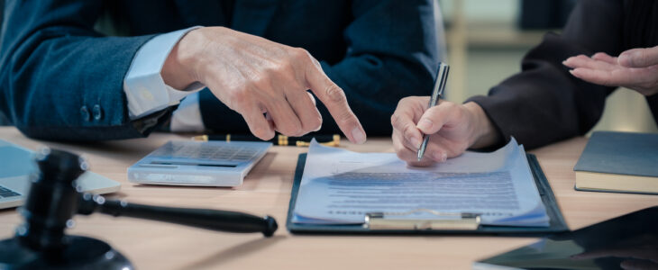 Law office with legal books and scales on table. Legal consultation: lawyer and client reviewing documents together. Representing trusts and legal proceedings. Close-up.