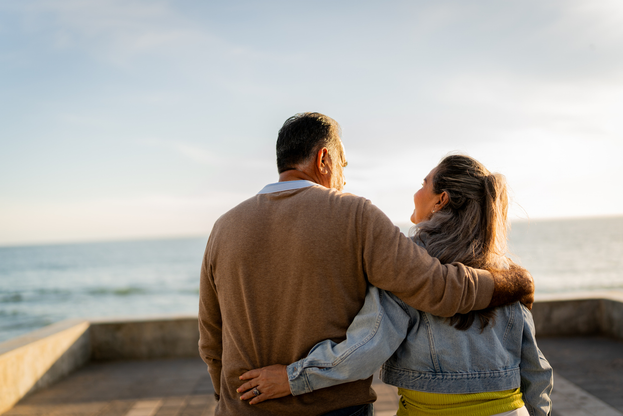 Senior couple walking and talking on coastline pier