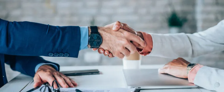 Cropped shot of unrecognizable business persons shaking hands after signing a contract. Business people shaking hands in the office.