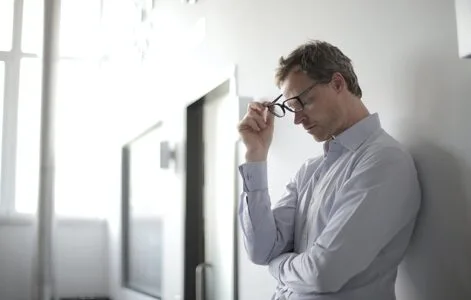 Stressed man holding glasses